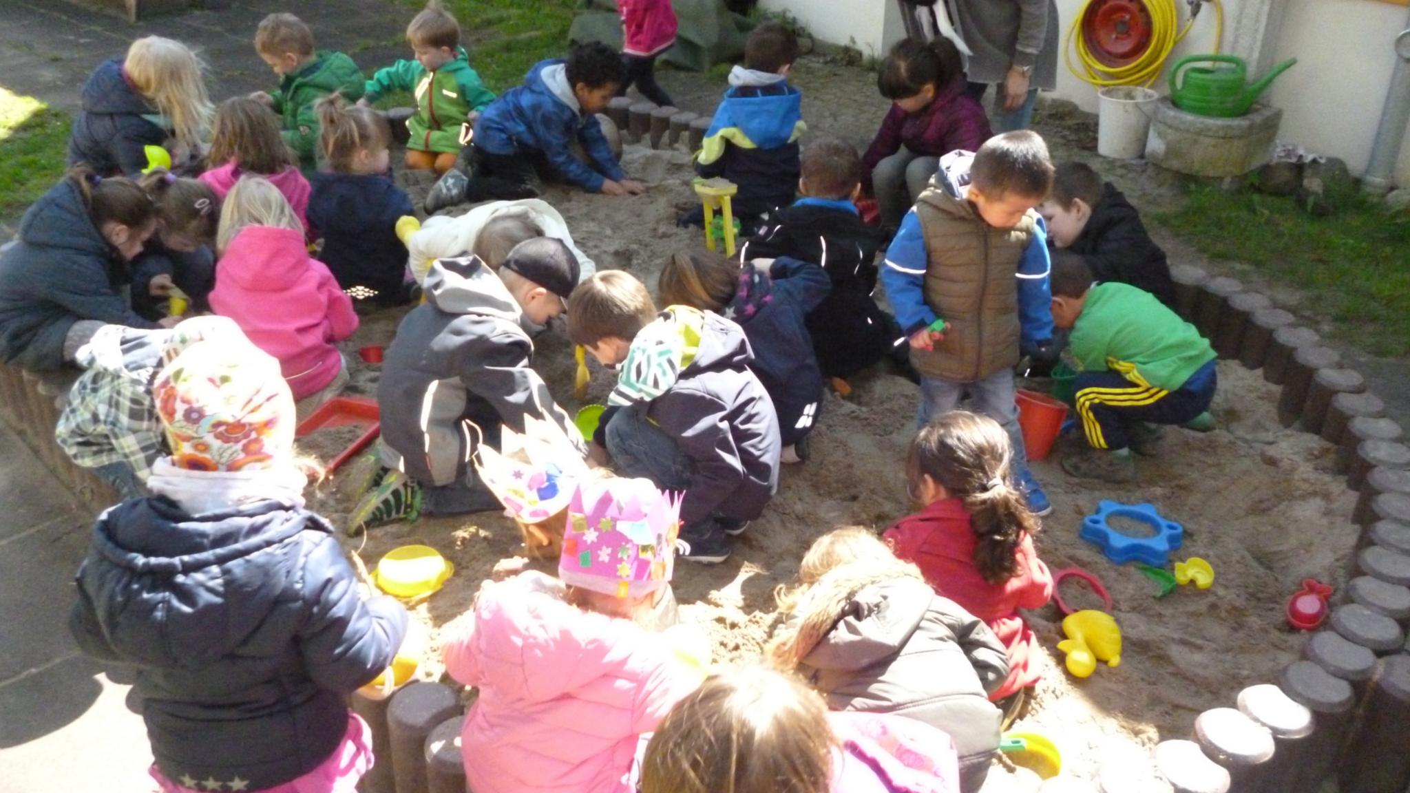 viele Kinder spielen im Sandkasten