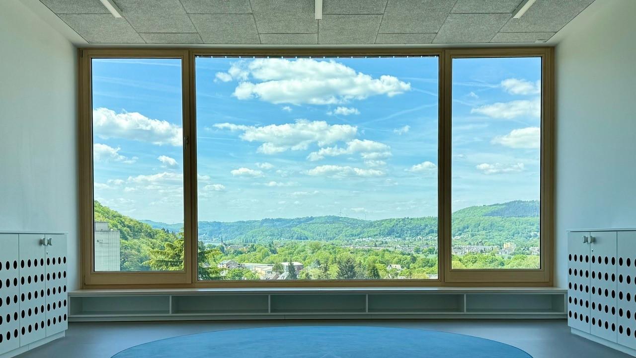 Man sieht ein großes Fenster mit Aussicht ins Grüne