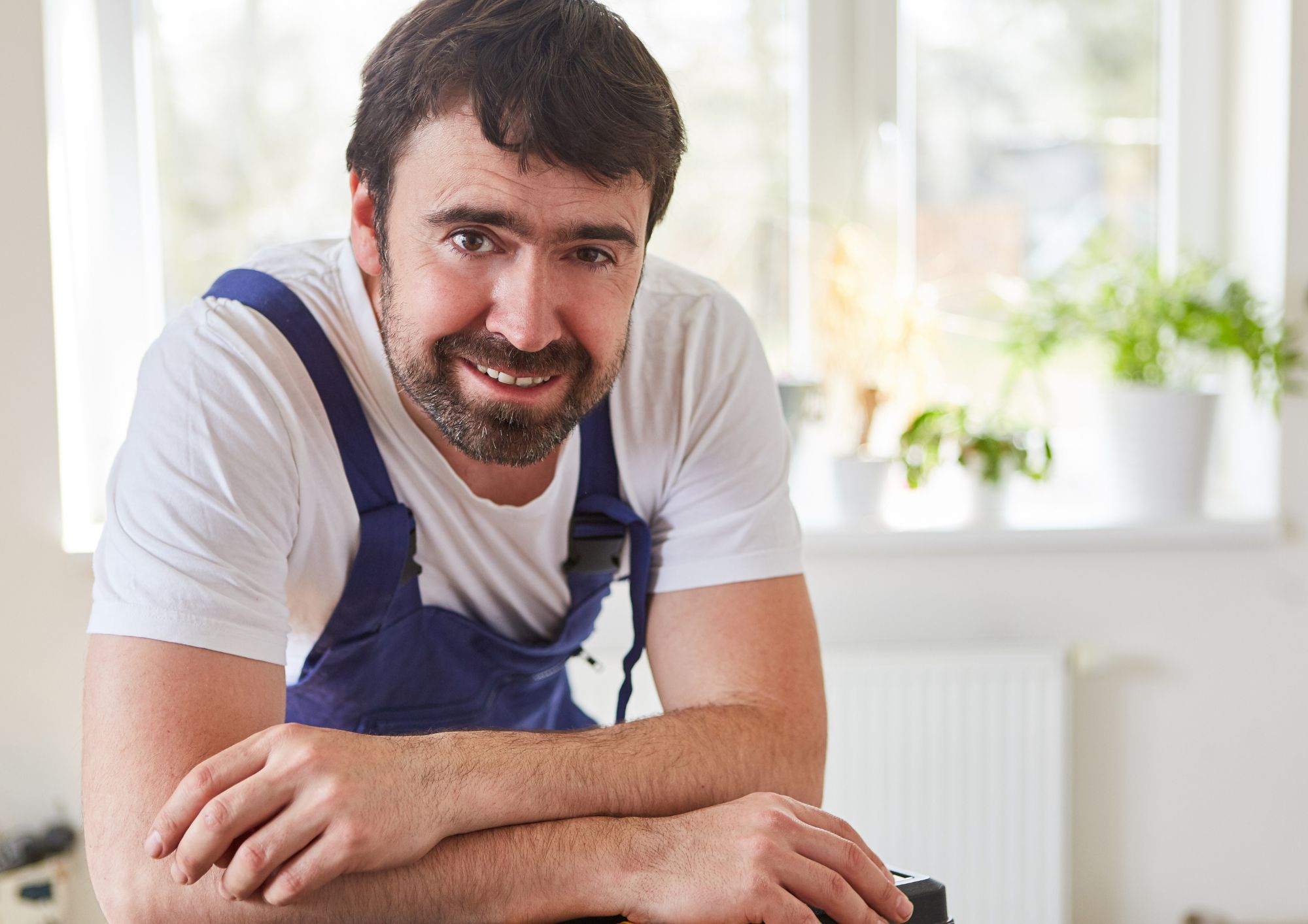 Ein Mann mit blauer Latzhose lächelt in die Kamera