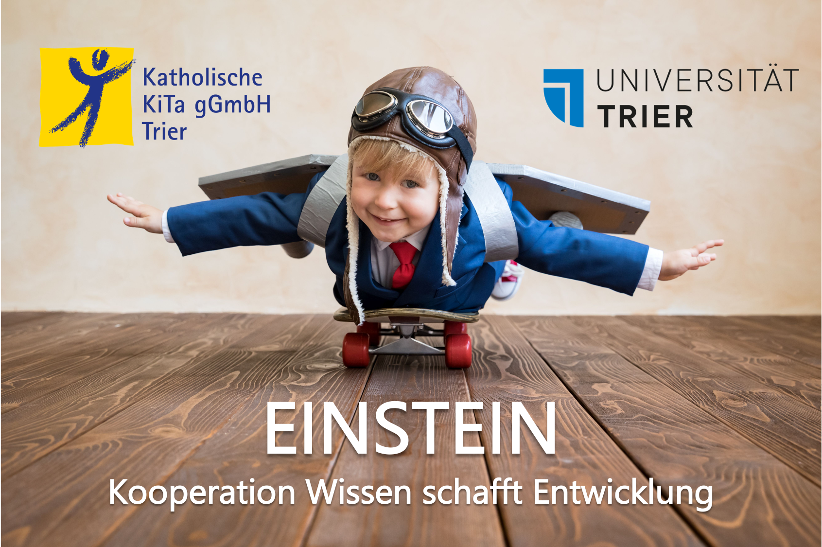 Man sieht ein Kind in Pilotenverkleidung auf einem Skateboard liegend. Die Logos der Universität Trier und der katholischen KiTa gGmbH Trier sind ebenfalls zu sehen.