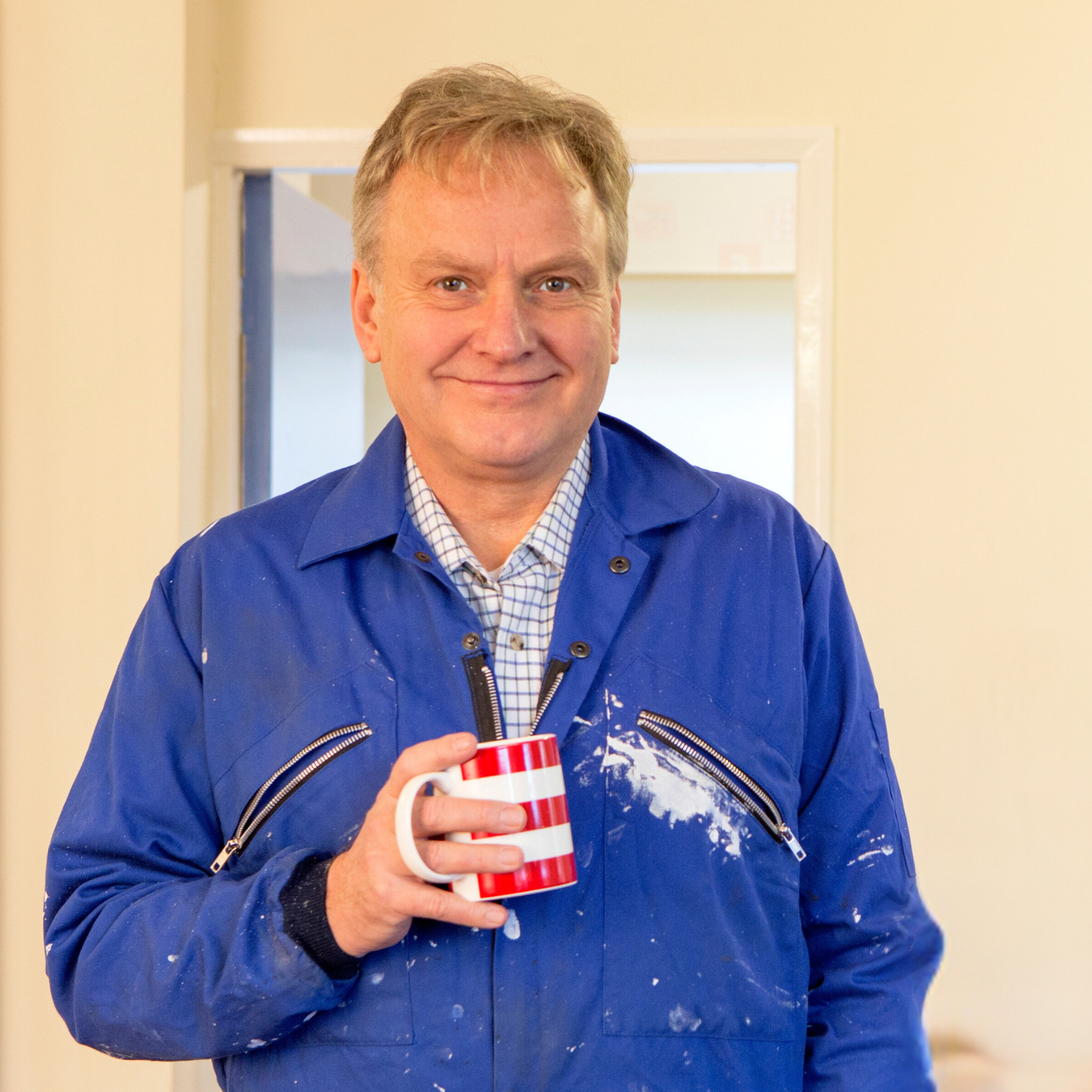 Mann in blauem Overall mit Tasse