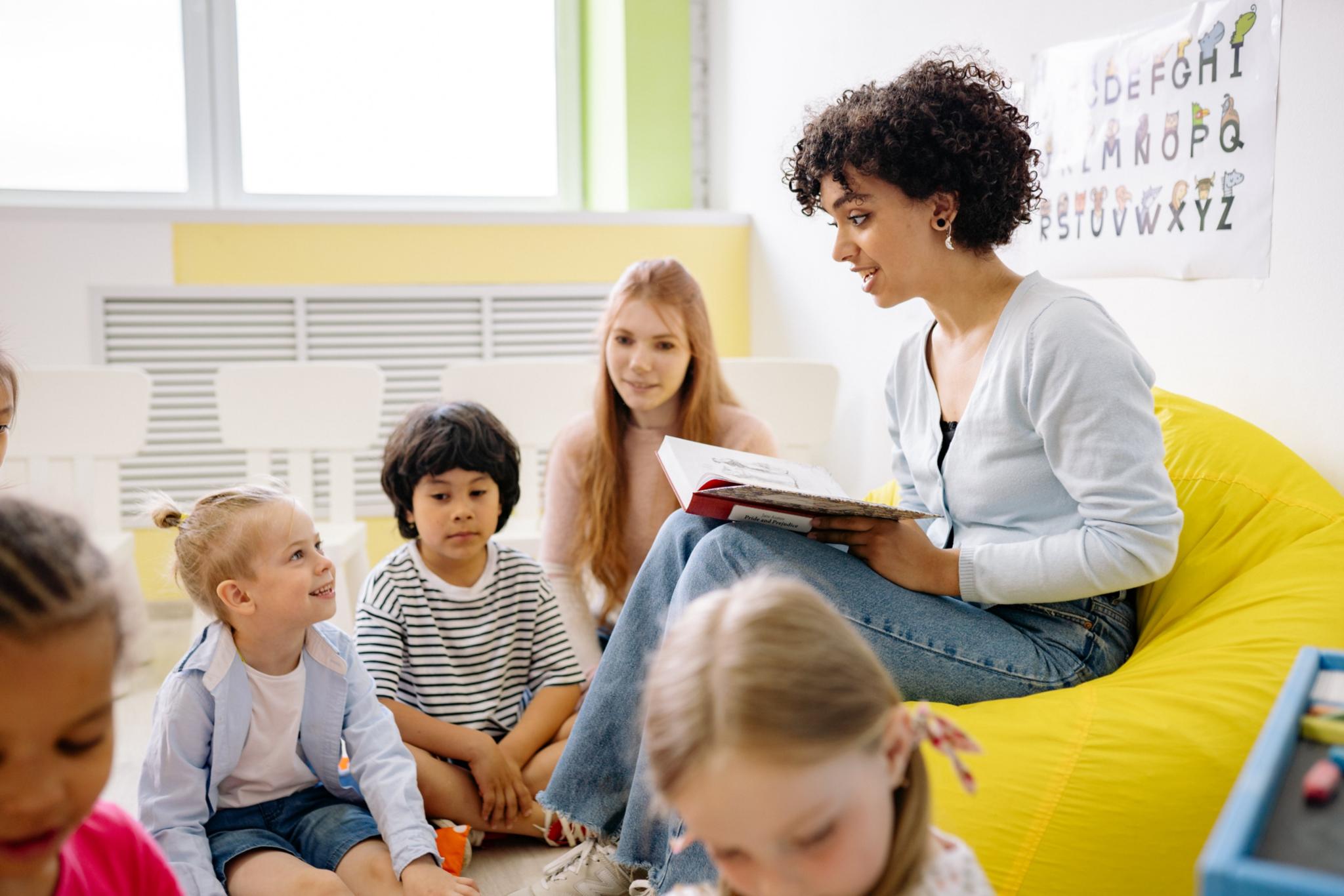 Junge Erzieherin liest kleinen Kindern vor